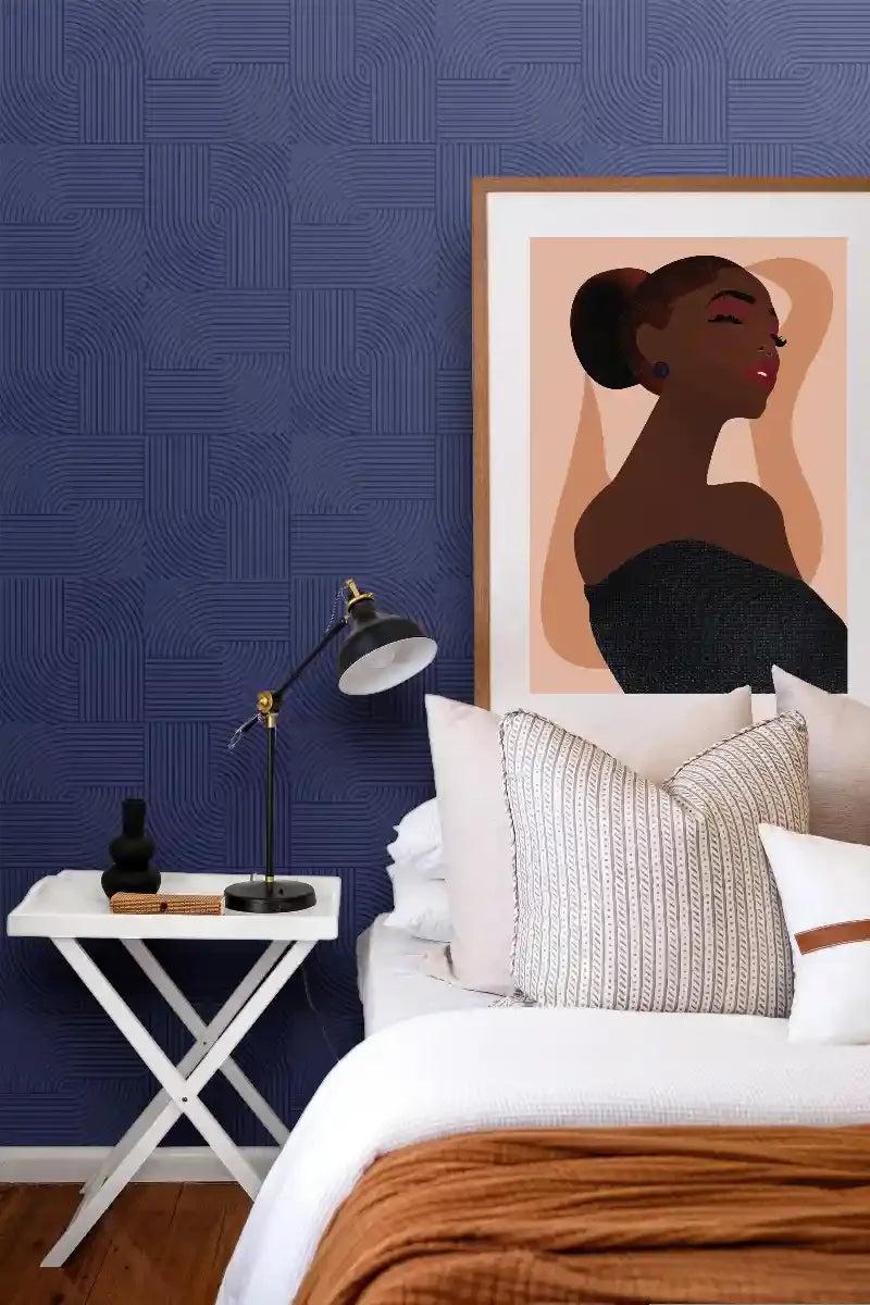 Modern bedroom with geometric blue wall panels, framed artwork, bed, and side table decor