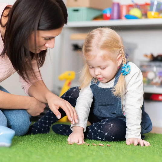 Childcare worker teaches a child with plywood letters.