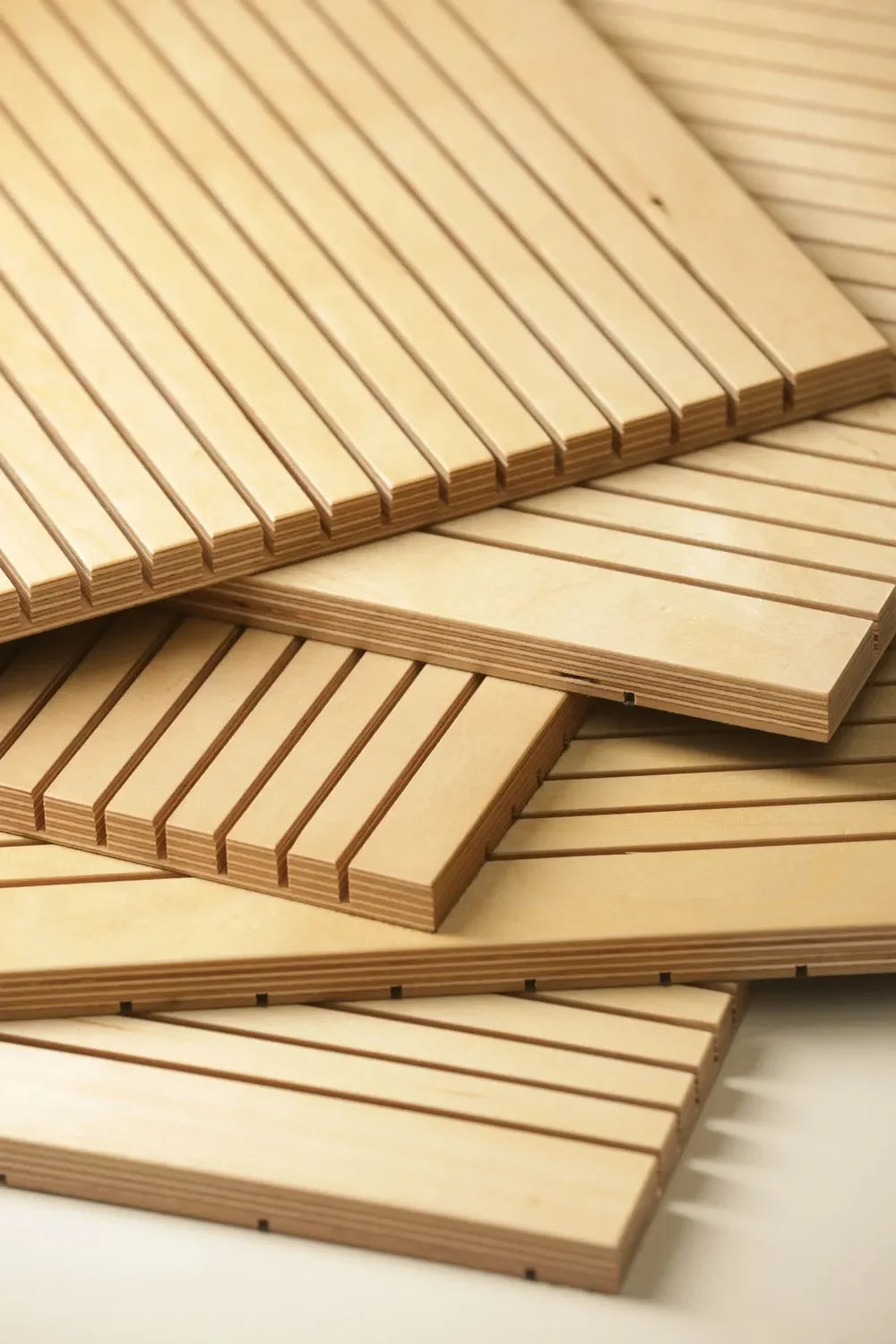Stack of grooved sound dampening plywood panels with light wood finish