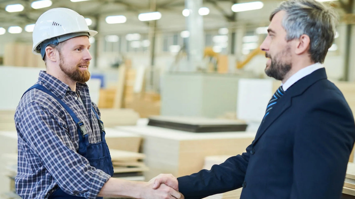 Two men shake hands in plywood factory