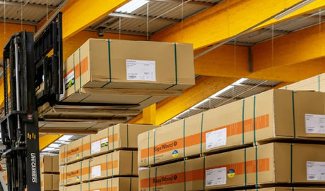 Forklift lifting plywood packaging boxes in a warehouse with timber beams