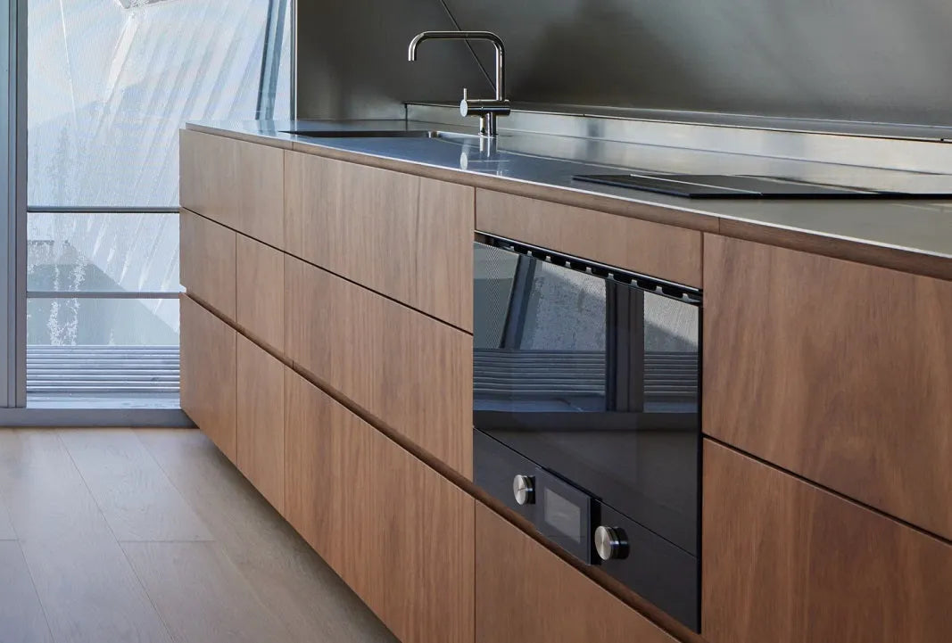 Modern kitchen with plywood cabinets, built-in oven, and stainless steel benchtop