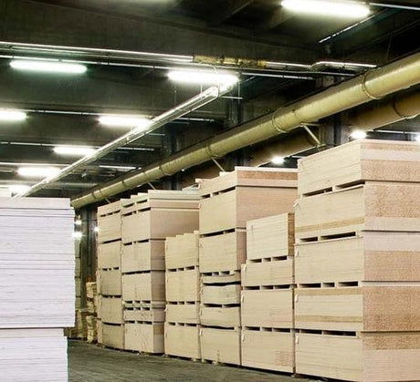 Stacks of plywood sheets in an industrial warehouse with fluorescent lighting