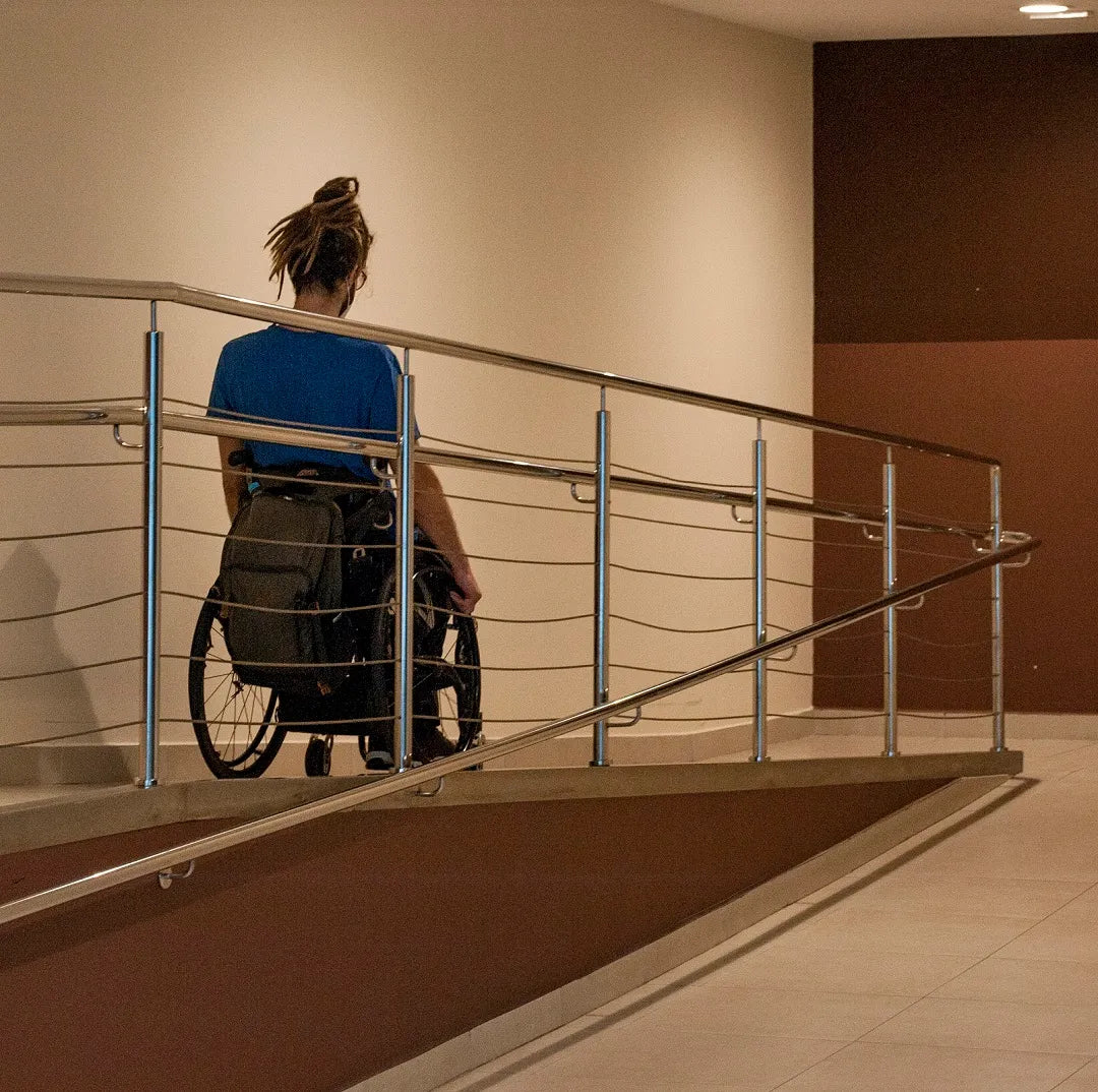 A man in a wheelchair is using a ramp, showcasing home modifications for improved accessibility.