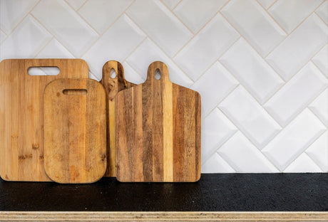 Cutting boards stay on the black plywood benchtop on the white tiles background