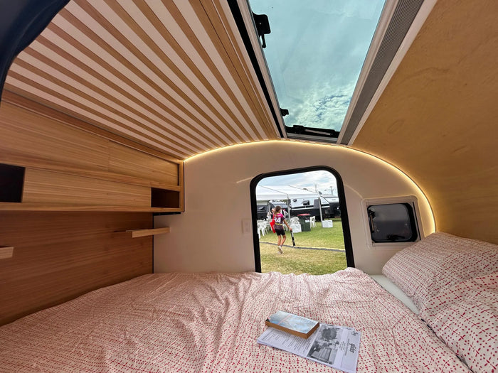 Plywood interior of a camper with a bed and skylight