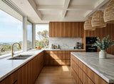 A modern L-shaped kitchen white marble countertops and backsplash, large windows with ocean views, woven pendant lights, and cabinetry made with Messmate Timber Veneer Panel A/B UV-Coated FOSB 19x2745x1220 mm - Ply Online.