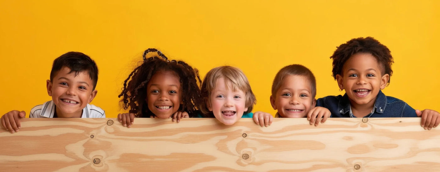 Five children of various ethnicities holding a plywood board against a yellow background 