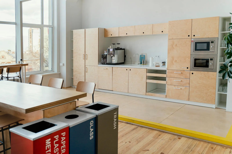 Modern kitchen with birch plywoodn cabinets and a recycling bin system.